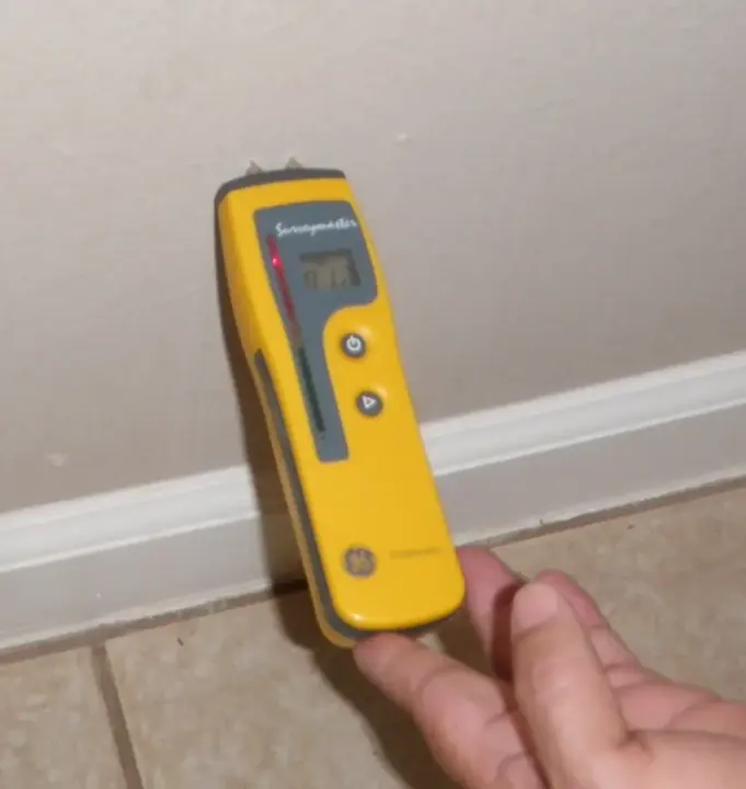 Pin moisture meter reading a baseboard during a Redding water damage check
